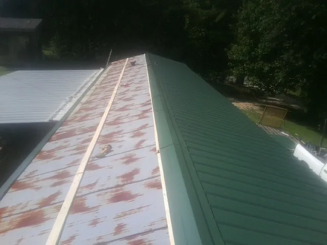 Old rusted panels beside newly installed green metal roofing — Wind Damage Roof Repair by Roofing Brothers in Gorham