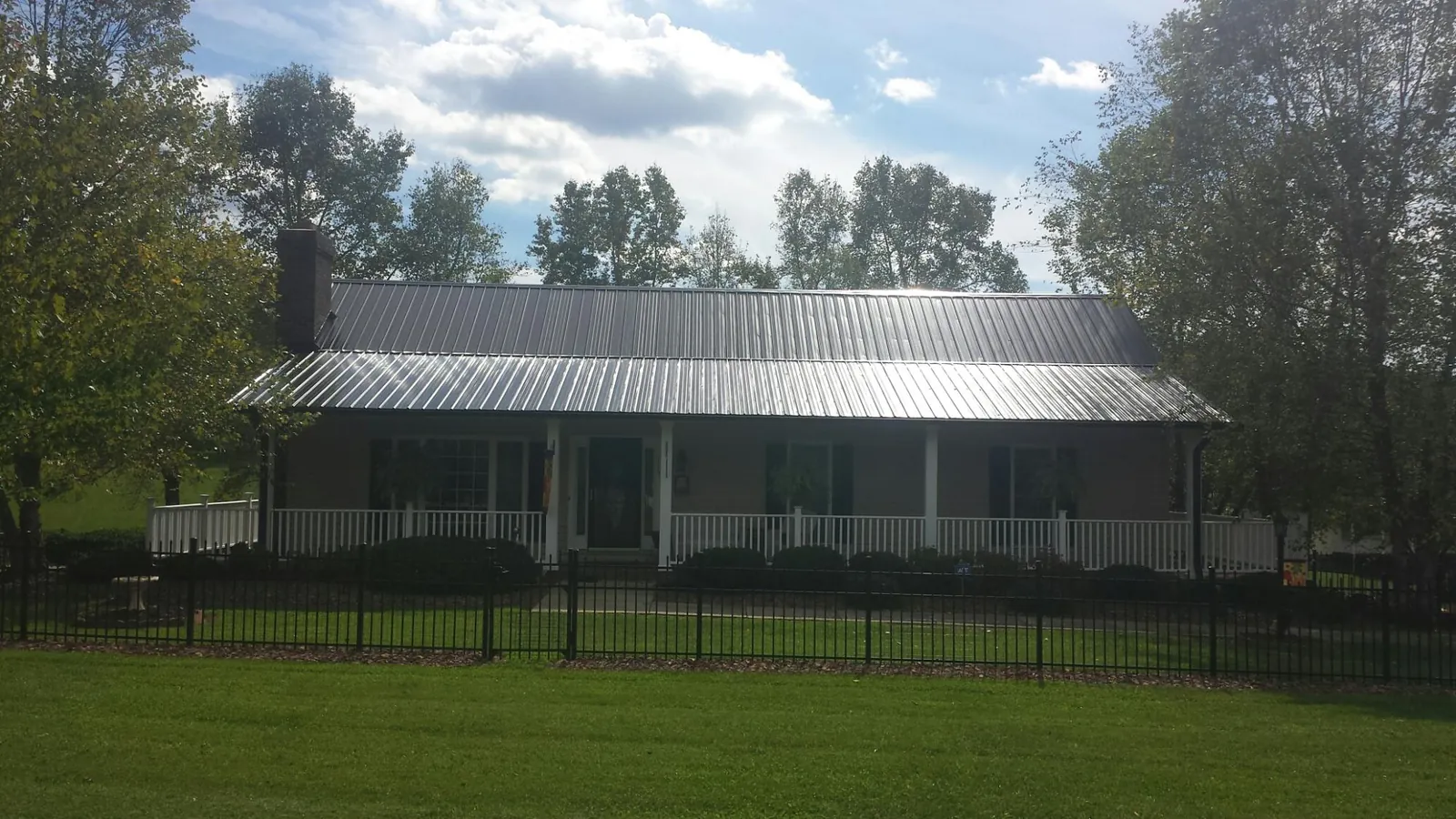 Gray metal roof on a brick ranch with a full width front porch — Gutter Guard Installation work by our crew in Gorham