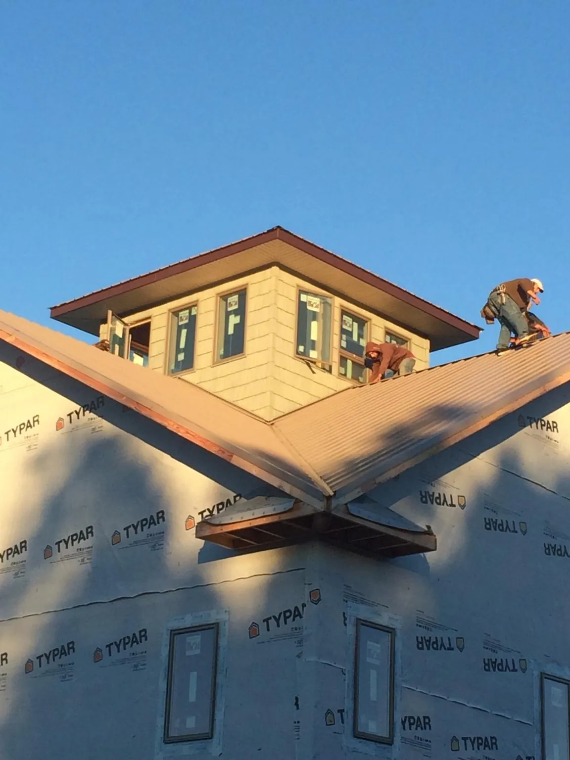 Roofers working around a rooftop cupola on a new metal roof at sunset — Roof Waterproofing in Gorham by Roofing Brothers